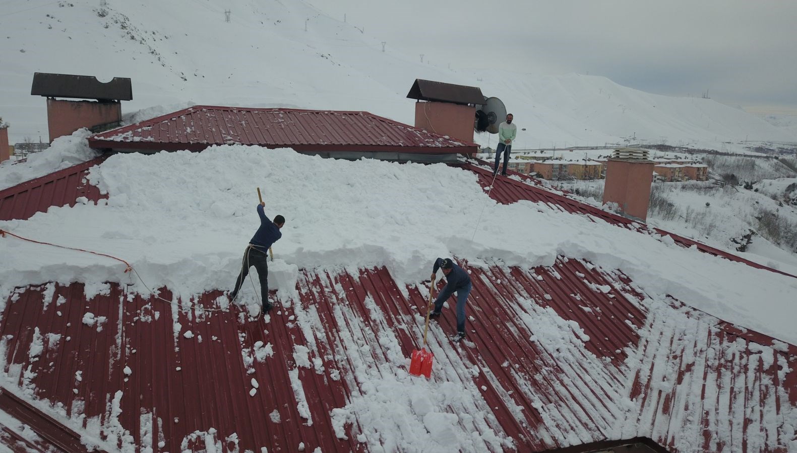 bellerine bagladiklari iplerle catilardan kar temizliyorlar